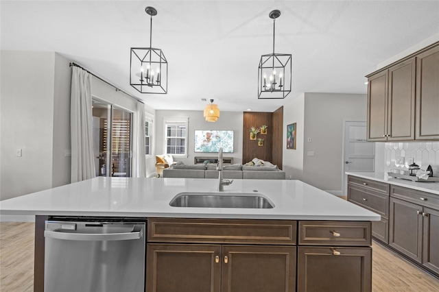 kitchen with a sink, light wood-style flooring, light countertops, and stainless steel dishwasher