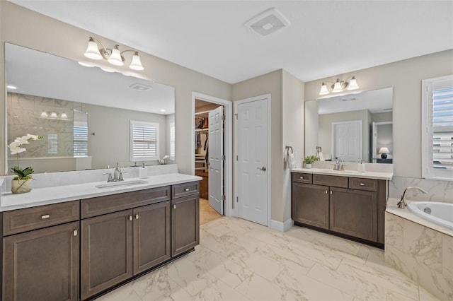 bathroom with a bath, marble finish floor, two vanities, and a sink