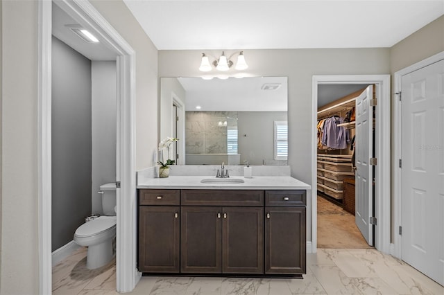 full bathroom with vanity, a spacious closet, toilet, and marble finish floor