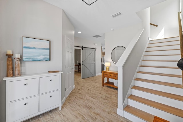 stairs with visible vents, baseboards, a barn door, recessed lighting, and wood finished floors