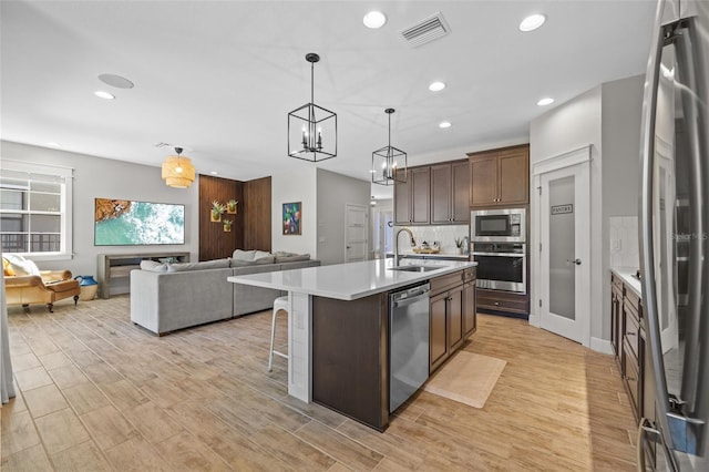 kitchen featuring visible vents, a sink, light countertops, appliances with stainless steel finishes, and open floor plan