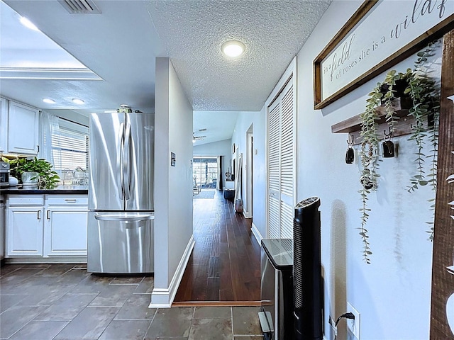 hall featuring visible vents, baseboards, and a textured ceiling