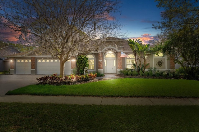 view of front of house with a garage, brick siding, concrete driveway, and a front lawn