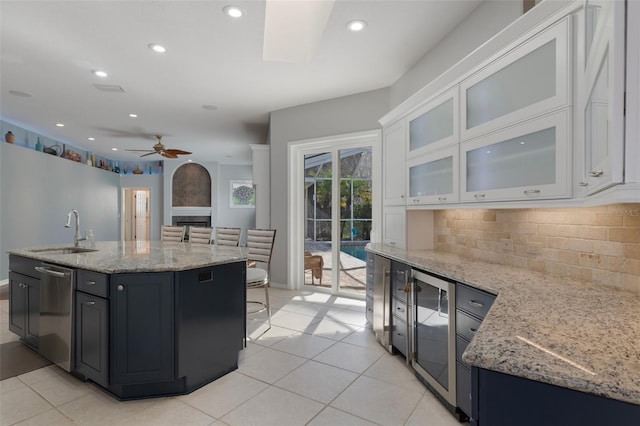 kitchen featuring a sink, decorative backsplash, light stone counters, and white cabinetry