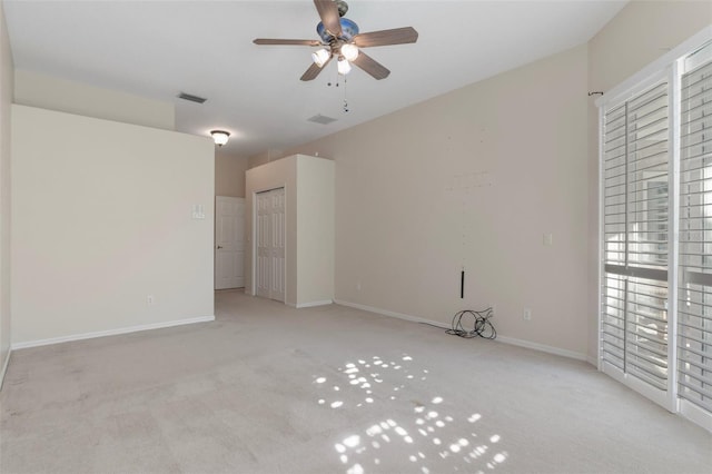 empty room with a ceiling fan, carpet flooring, baseboards, and visible vents