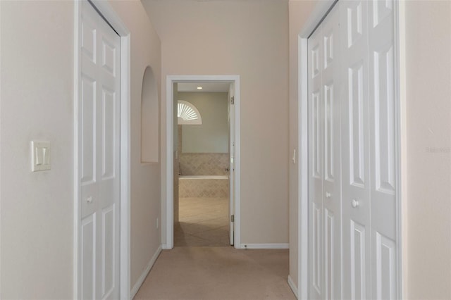 corridor featuring baseboards and light carpet