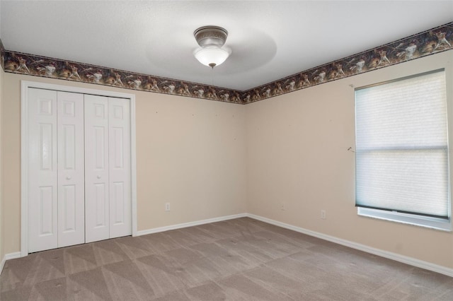 unfurnished bedroom with baseboards, carpet floors, a closet, and a ceiling fan