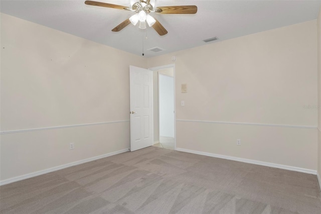 carpeted spare room featuring visible vents, a ceiling fan, and baseboards