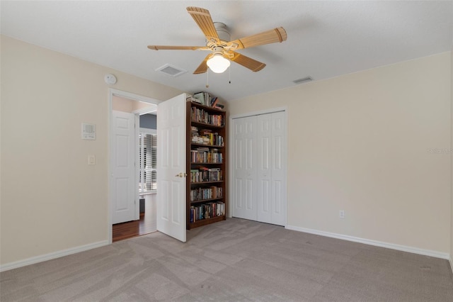 unfurnished room with visible vents, light colored carpet, baseboards, and ceiling fan