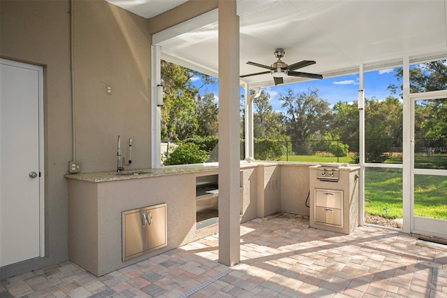 unfurnished sunroom featuring a sink, plenty of natural light, and a ceiling fan