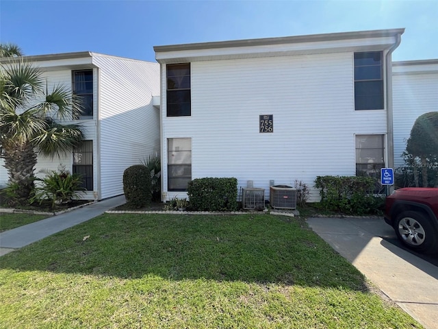 view of side of property with central AC unit and a lawn