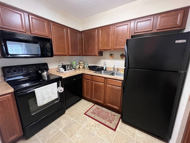 kitchen featuring a textured ceiling, black appliances, light countertops, and a sink