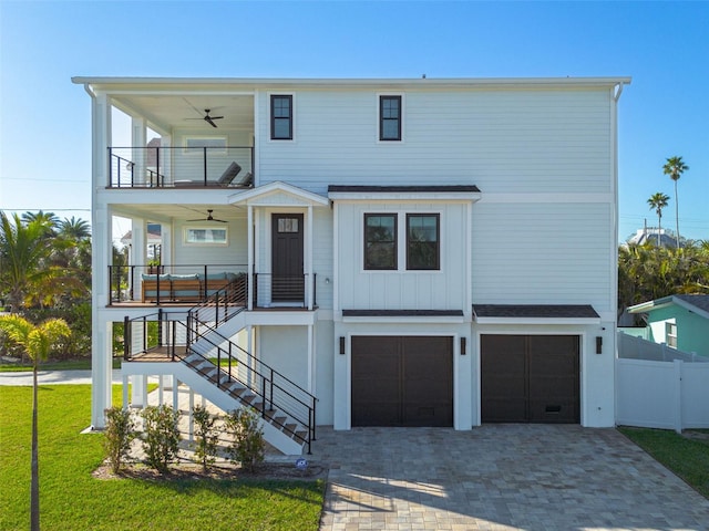 beach home with a balcony, fence, ceiling fan, decorative driveway, and board and batten siding