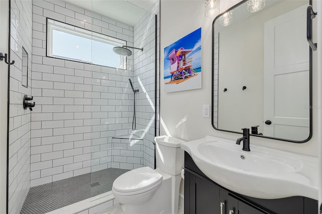 bathroom with vanity, toilet, and a tile shower