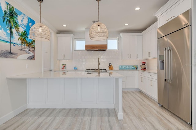 kitchen with tasteful backsplash, light wood finished floors, light countertops, appliances with stainless steel finishes, and white cabinetry