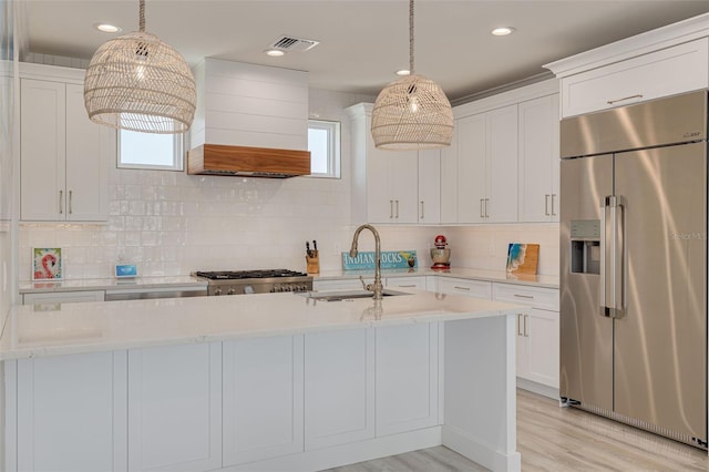 kitchen with visible vents, stainless steel refrigerator with ice dispenser, custom range hood, a sink, and stove