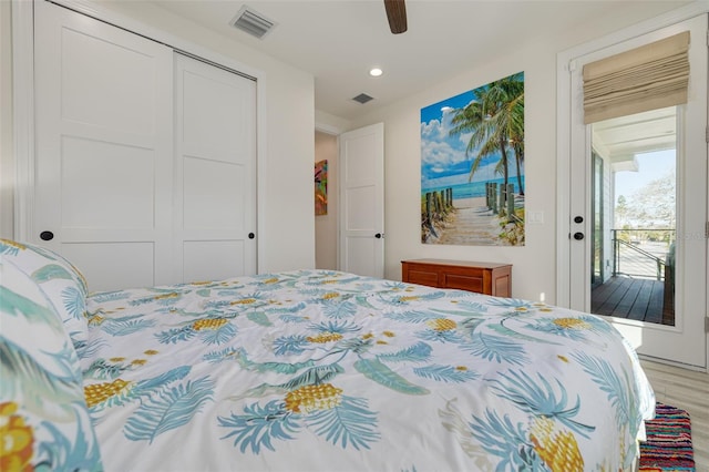 bedroom with light wood-type flooring, visible vents, a closet, and a ceiling fan