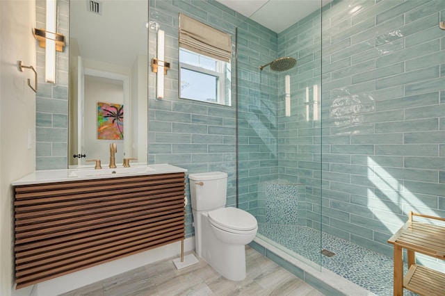 bathroom featuring visible vents, a walk in shower, toilet, and vanity