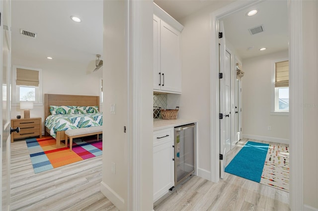 interior space featuring visible vents, a healthy amount of sunlight, beverage cooler, and light wood-style flooring