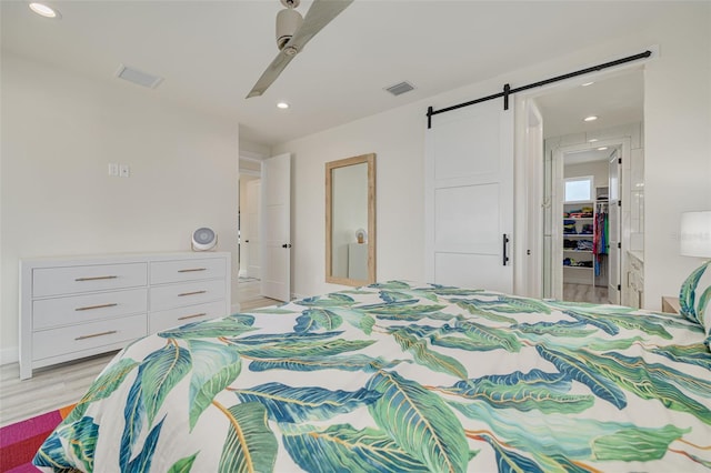 bedroom with light wood-type flooring, visible vents, a ceiling fan, recessed lighting, and a barn door