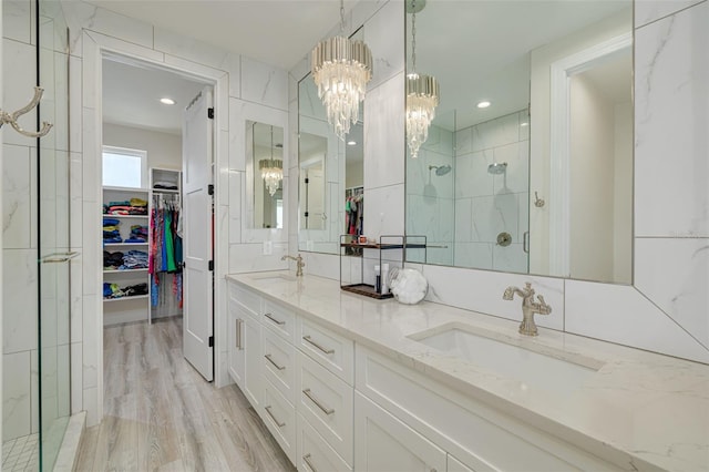 full bath featuring a marble finish shower, a notable chandelier, a spacious closet, and a sink