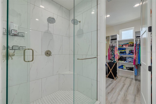 full bathroom with a walk in closet, wood finished floors, and a stall shower