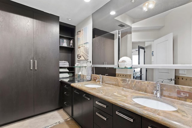 bathroom featuring tile patterned floors, visible vents, double vanity, and a sink