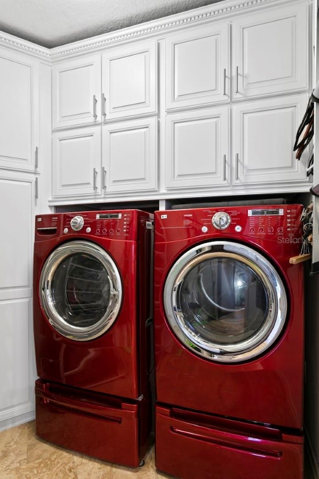 clothes washing area featuring cabinet space and washing machine and clothes dryer