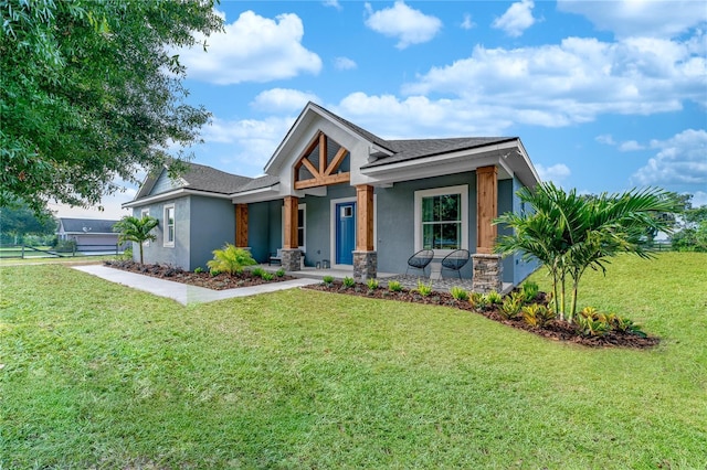 view of front of house featuring covered porch, stucco siding, a shingled roof, and a front lawn