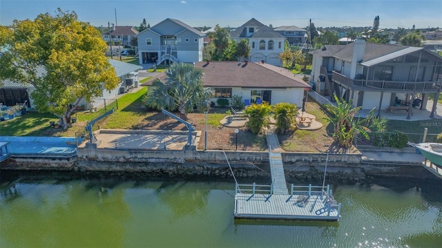 view of dock featuring a water view, a lawn, a patio, a fenced backyard, and a residential view