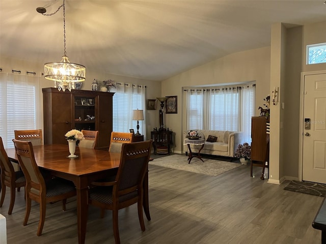 dining space featuring an inviting chandelier, baseboards, lofted ceiling, and wood finished floors