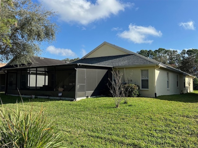 rear view of property with a yard, a shingled roof, stucco siding, and a sunroom