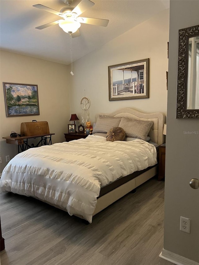 bedroom with a ceiling fan, lofted ceiling, and wood finished floors