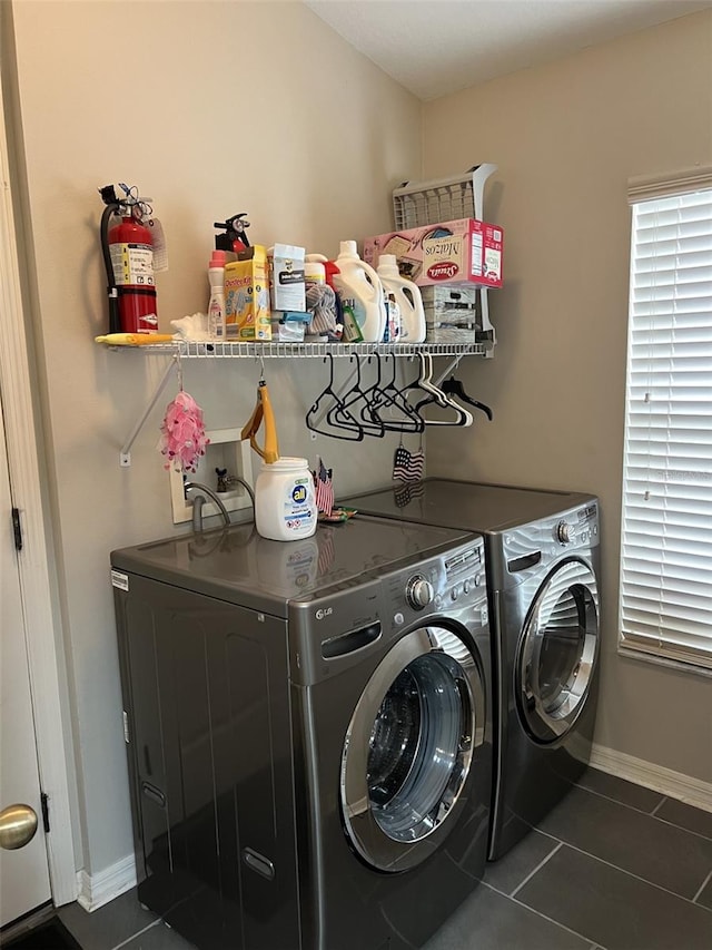 laundry area featuring washer and dryer, laundry area, dark tile patterned flooring, and baseboards