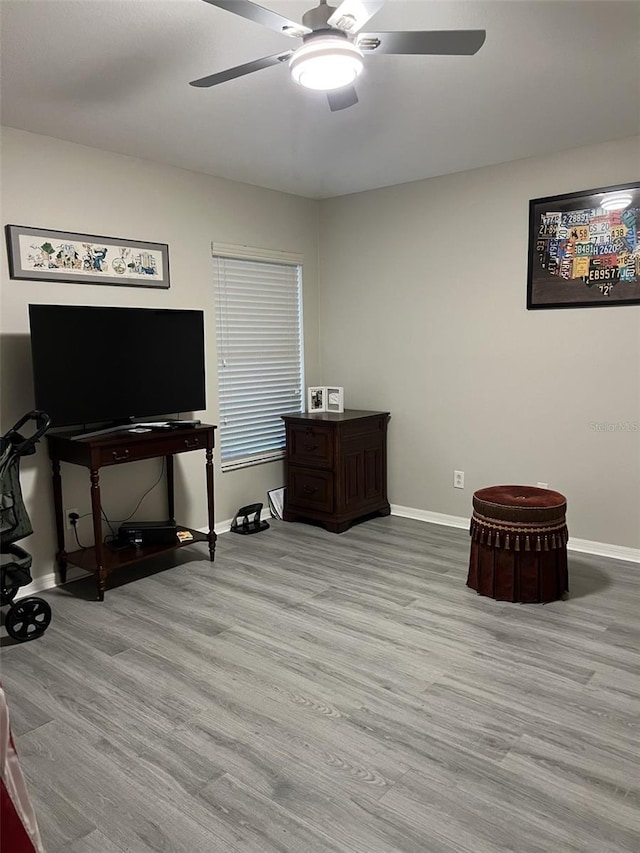 interior space featuring a ceiling fan, baseboards, and wood finished floors