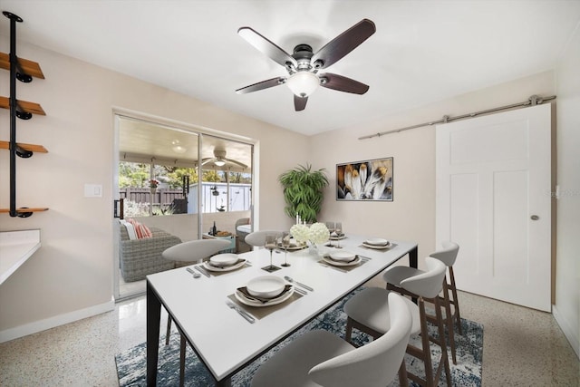 dining space with a barn door, light speckled floor, baseboards, and ceiling fan