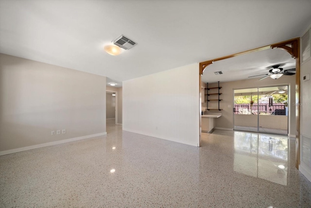 unfurnished room with visible vents, speckled floor, and baseboards