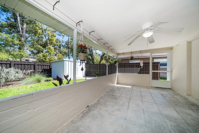 view of patio with an outbuilding, a storage unit, a ceiling fan, and a fenced backyard