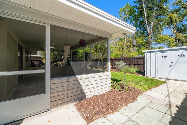 view of patio / terrace featuring a shed, fence, an outdoor structure, and a sunroom