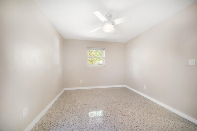 unfurnished room with baseboards, speckled floor, and ceiling fan