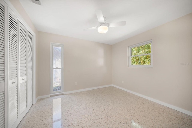 unfurnished bedroom featuring visible vents, a ceiling fan, a closet, speckled floor, and baseboards