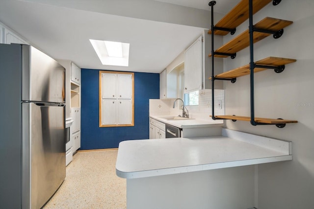 kitchen featuring open shelves, a skylight, a peninsula, a sink, and stainless steel appliances