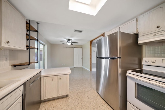 kitchen with light countertops, decorative backsplash, appliances with stainless steel finishes, a peninsula, and light speckled floor