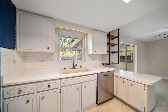 kitchen with a sink, light speckled floor, stainless steel dishwasher, a peninsula, and light countertops