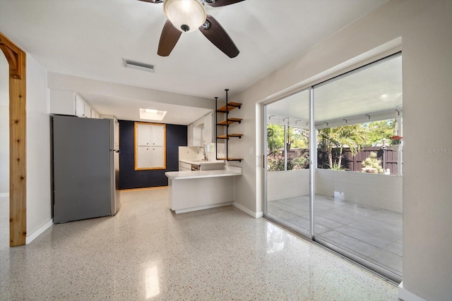 interior space featuring visible vents, light speckled floor, baseboards, and a sink