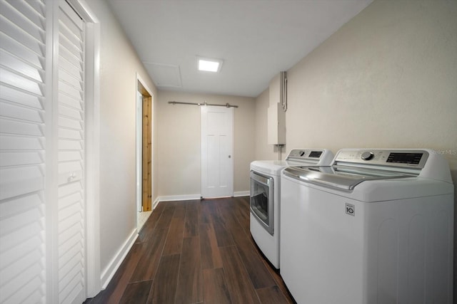 washroom with a barn door, washing machine and dryer, dark wood-type flooring, and baseboards