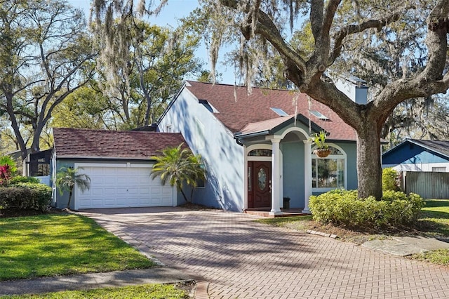 view of front of house with stucco siding, decorative driveway, fence, an attached garage, and a shingled roof