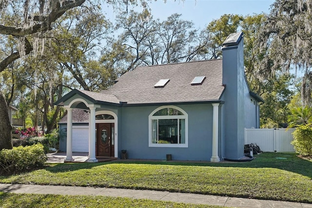 view of front of house featuring a shingled roof, a front yard, fence, and stucco siding