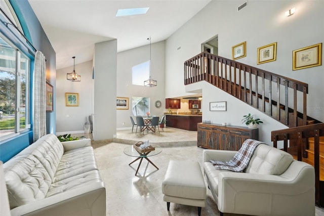 living area featuring visible vents, baseboards, stairway, a skylight, and a high ceiling