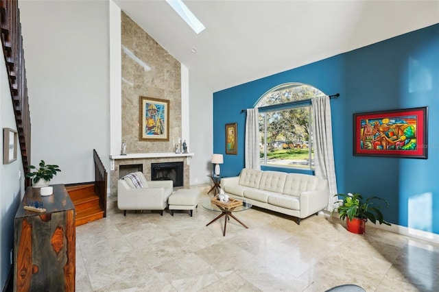 sitting room with high vaulted ceiling, a fireplace, a skylight, and baseboards